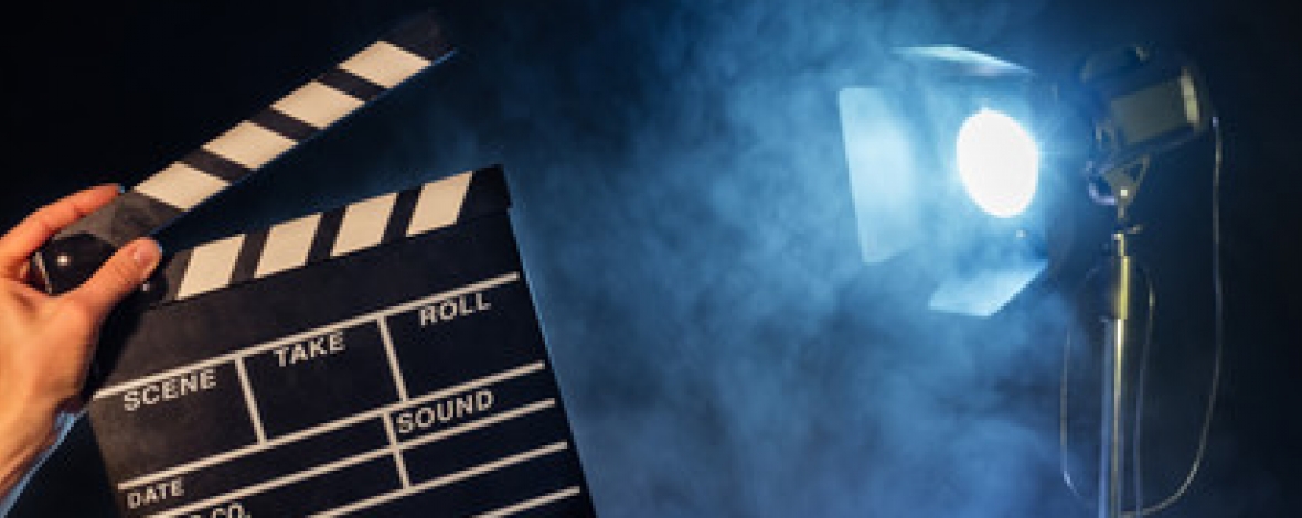 une main qui tient un clap avec un projecteur en arrière plan