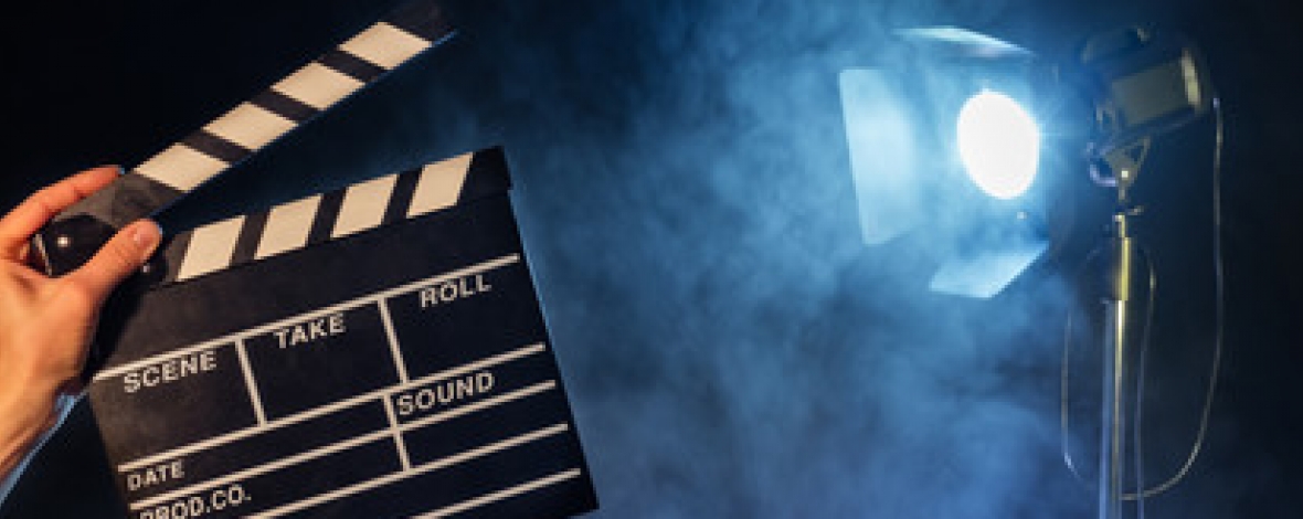 une main qui tient un clap avec un projecteur en arrière plan