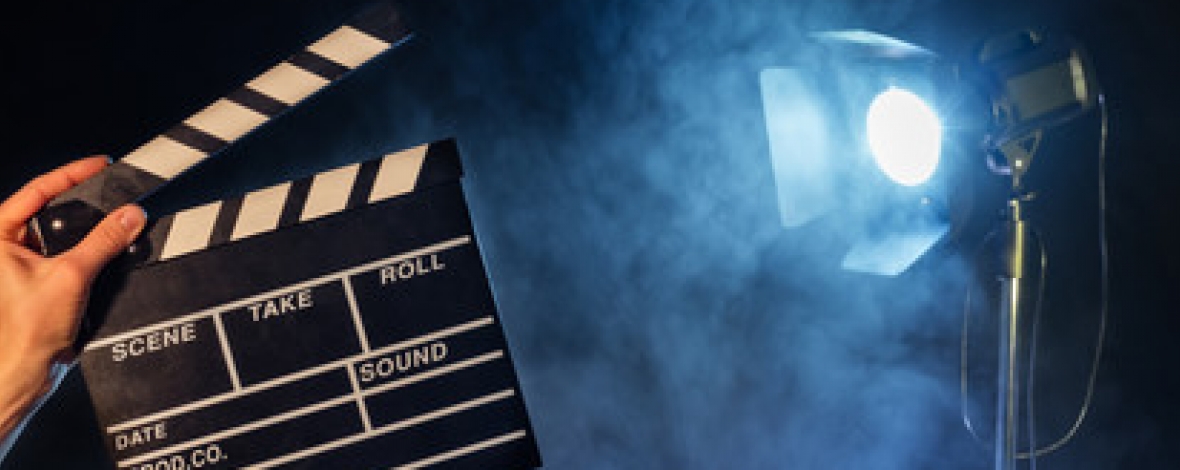 une main qui tient un clap avec un projecteur en arrière plan