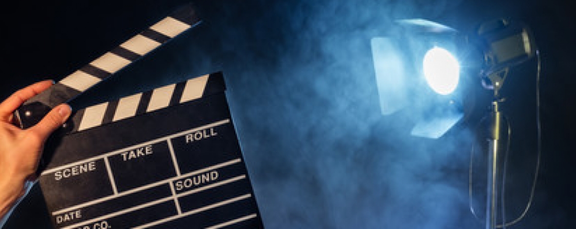 une main qui tient un clap avec un projecteur en arrière plan